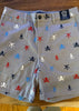 Beige shorts with colorful skull and crossbones pattern on a wooden surface