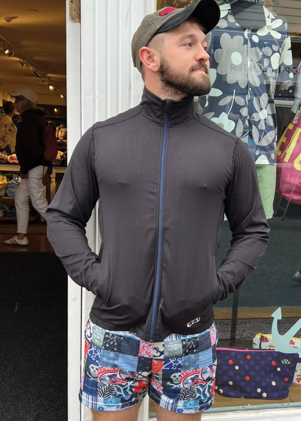 Man wearing a dark jacket and patterned shorts standing in a store.