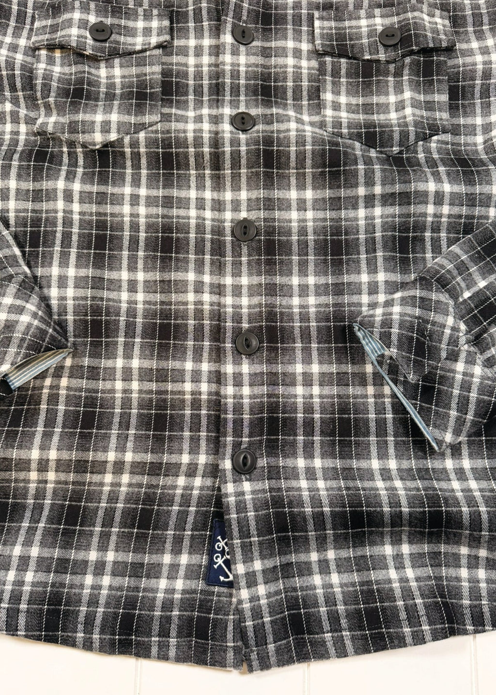 Black and white plaid shirt with button details on a white background