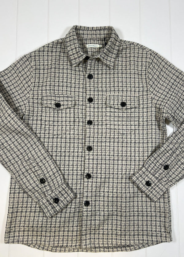 Plaid shirt with black buttons on a white wooden surface