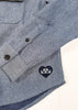 Blue herringbone patterned shirt with a logo on a white background