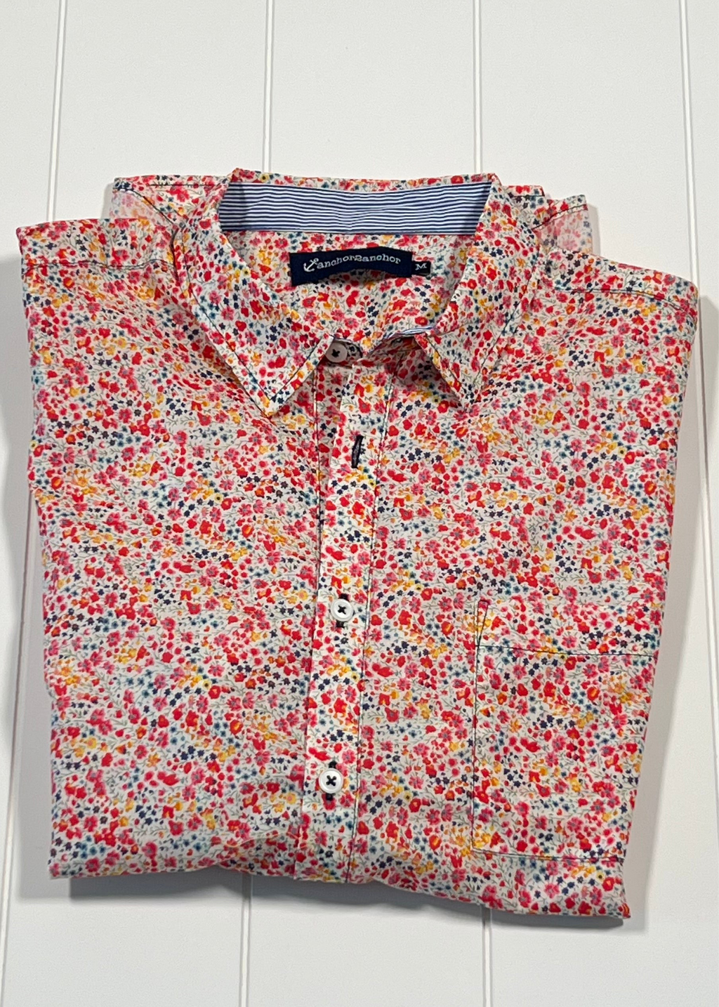 Folded floral shirt on a white wooden surface