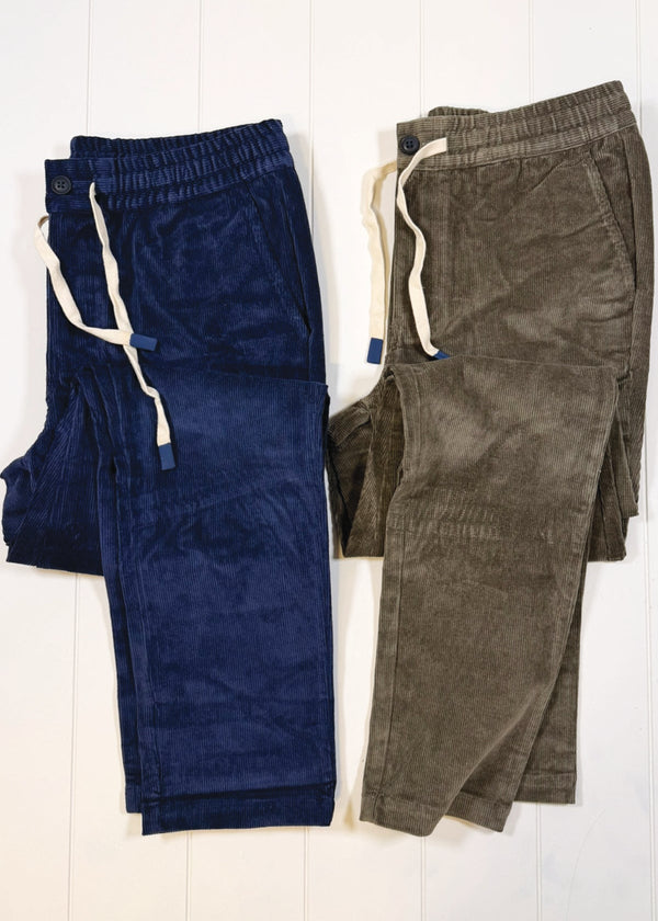 Two pairs of pants, one blue and one green, on a white background