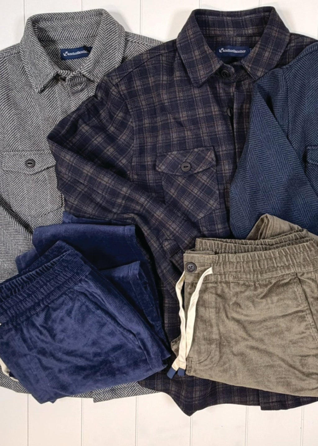 Collection of men's clothing including shirts and shorts on a white background