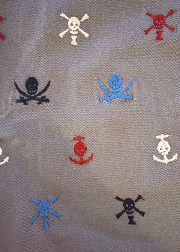 Pattern of embroidered skull and crossbones designs on a fabric background