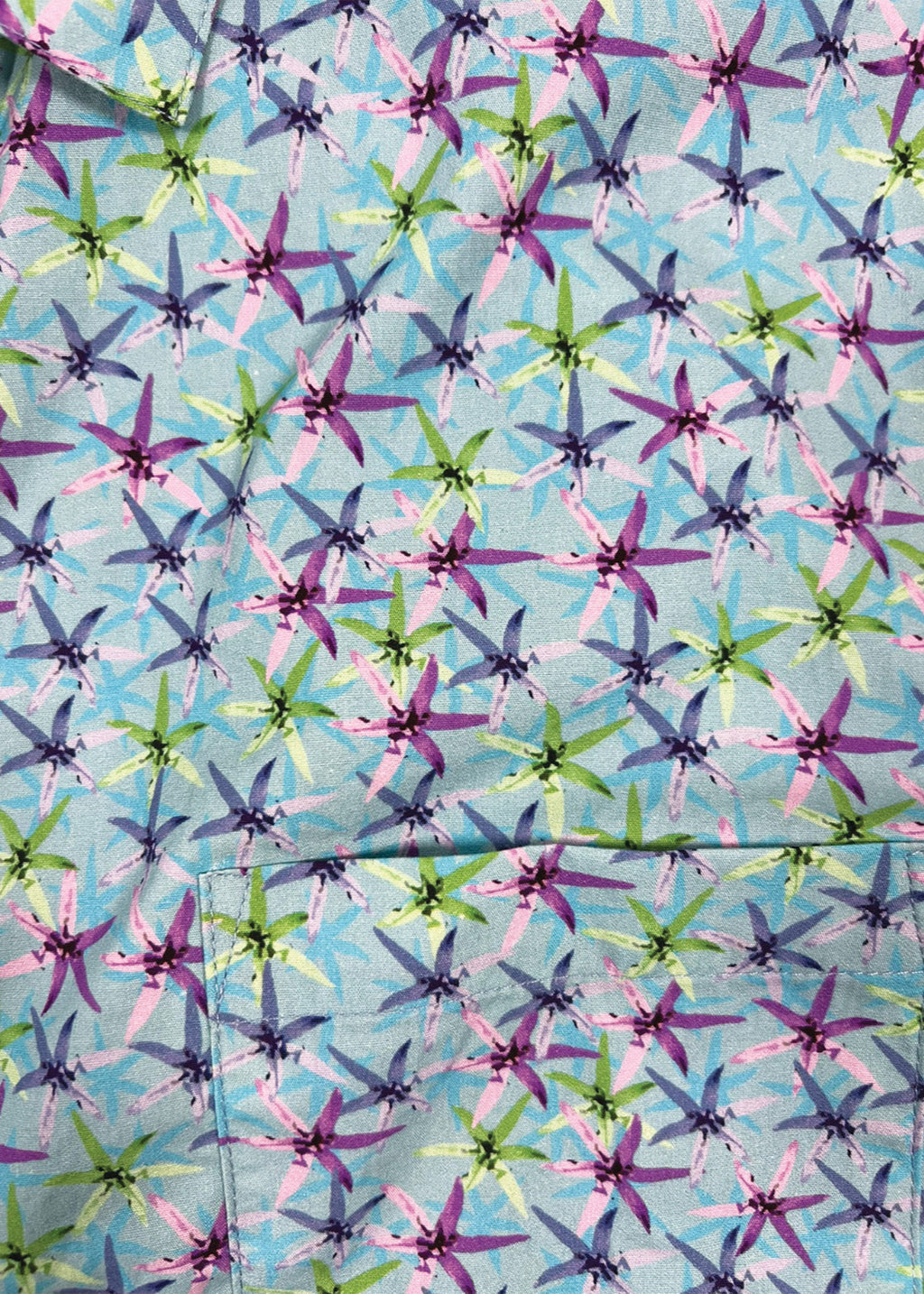 Patterned fabric with star shapes in purple, green, and blue on a light blue background