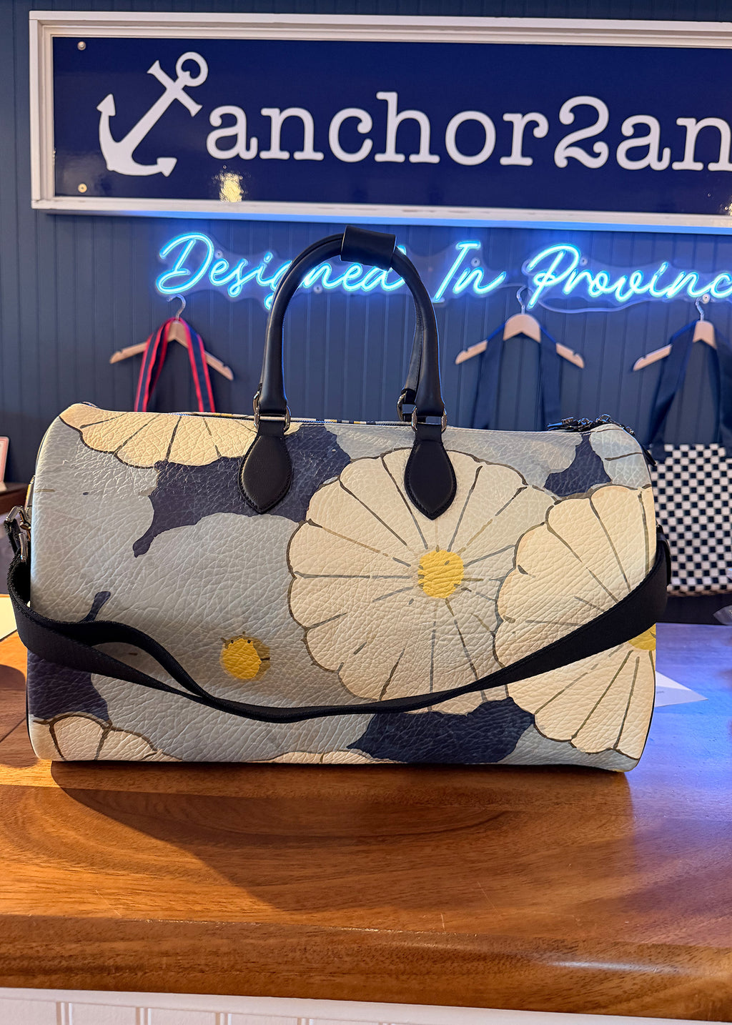 Floral-patterned bag on a wooden surface with a blurred background featuring 'anchor2an' branding.