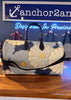 Floral-patterned bag on a wooden surface with a blurred background featuring 'anchor2an' branding.