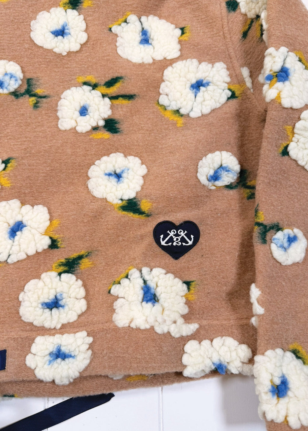 Brown fabric with white floral patterns and a black heart-shaped logo on a white background