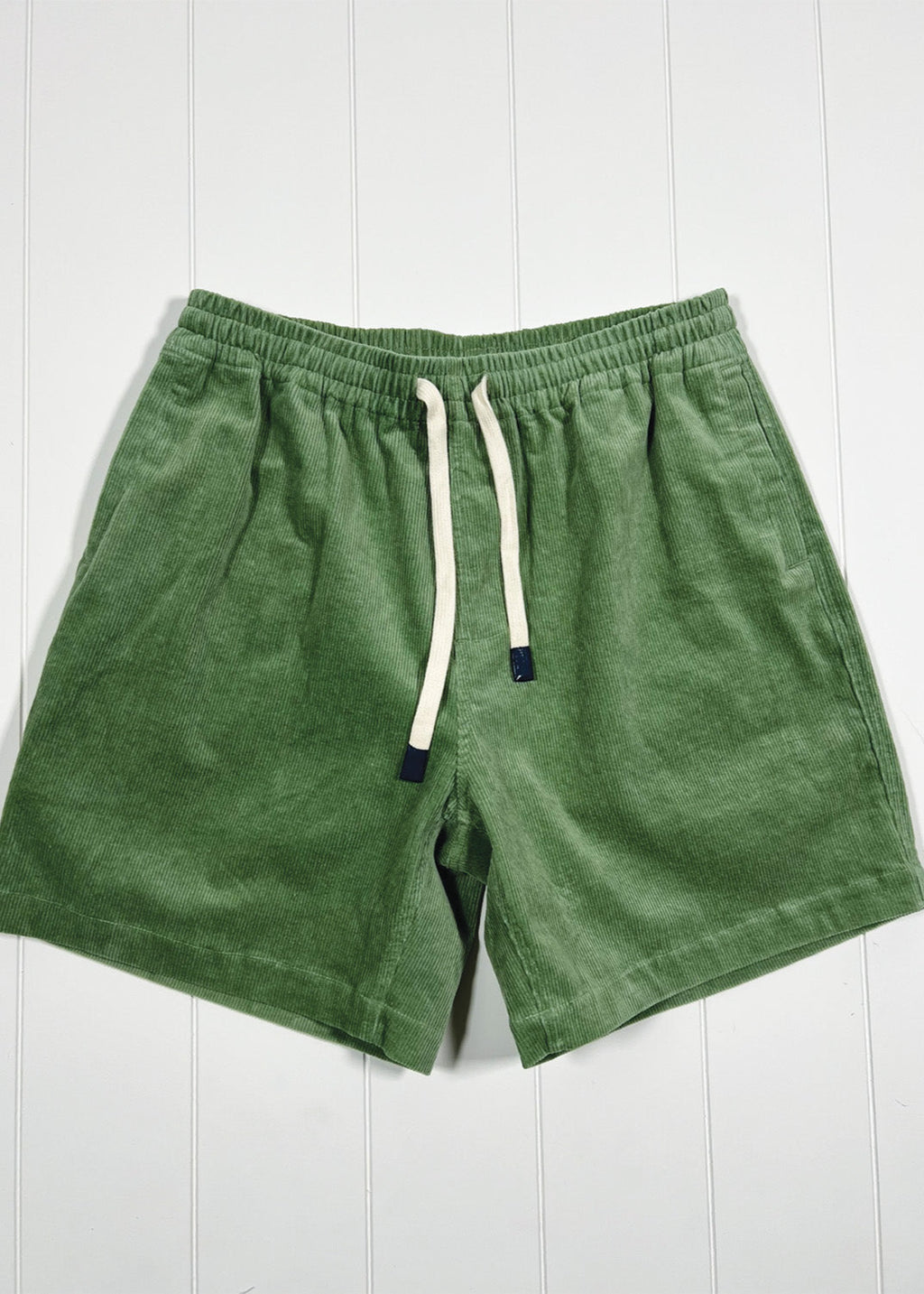 Green shorts with a drawstring on a white wooden background