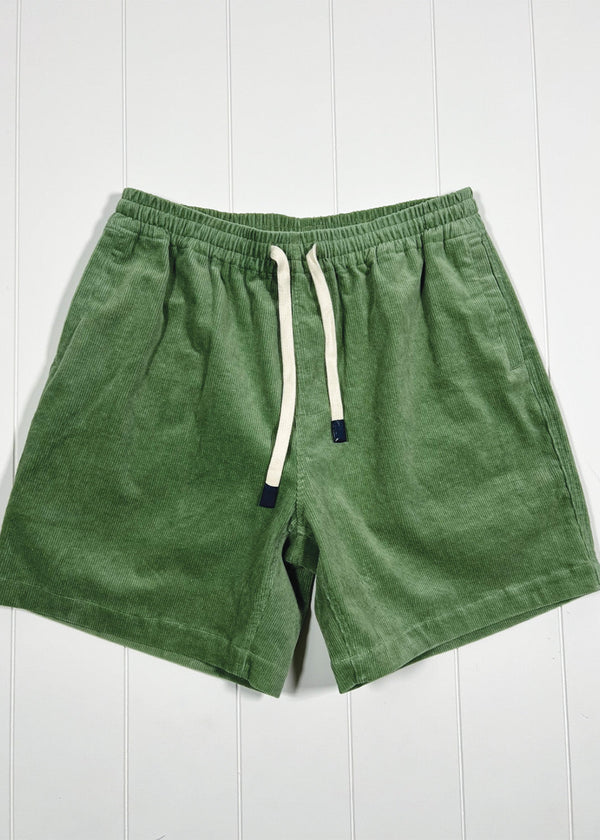 Green shorts with a drawstring on a white wooden background