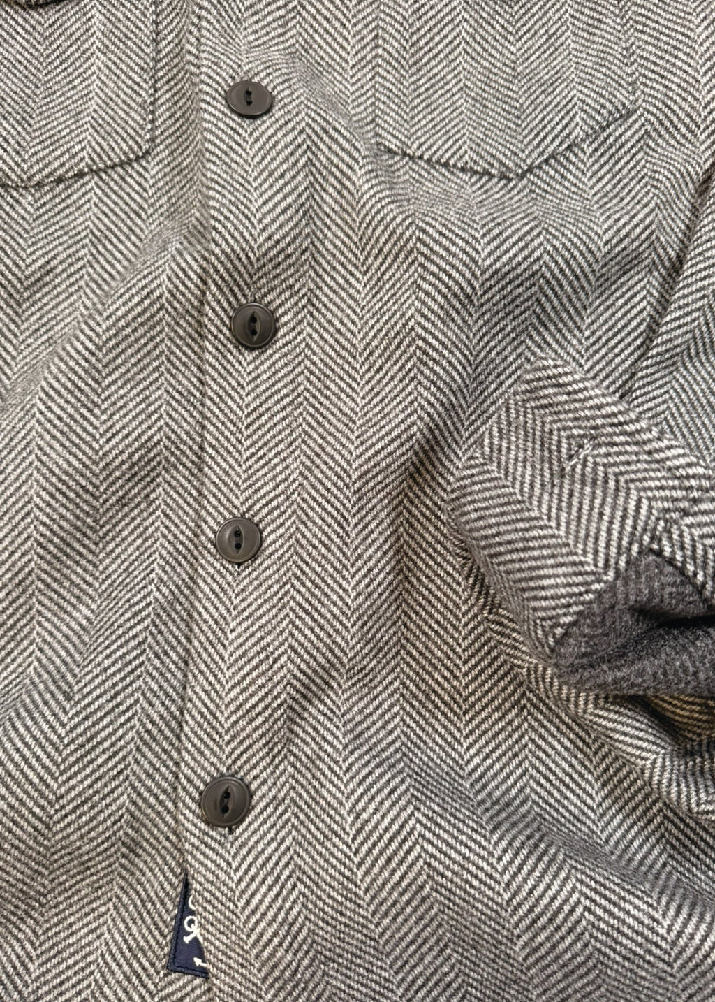 Close-up of a textured fabric with buttons on a herringbone pattern