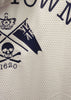 Close-up of a white textured fabric with a navy blue printed graphic featuring a crown, flag, skull and crossbones, and the number 1620.