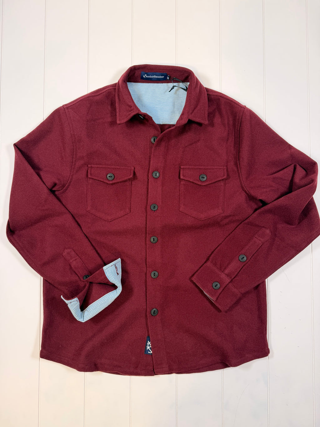 Folded maroon jacket on a light wooden surface