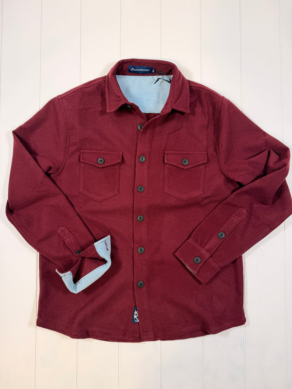 Folded maroon jacket on a light wooden surface