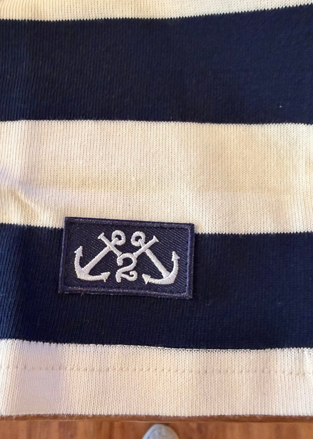 Navy and beige striped fabric with an anchor logo tag on a wooden surface