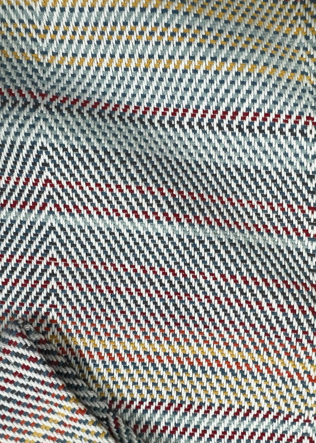 Close-up of fabric with a zigzag pattern in red, blue, and yellow on a gray background