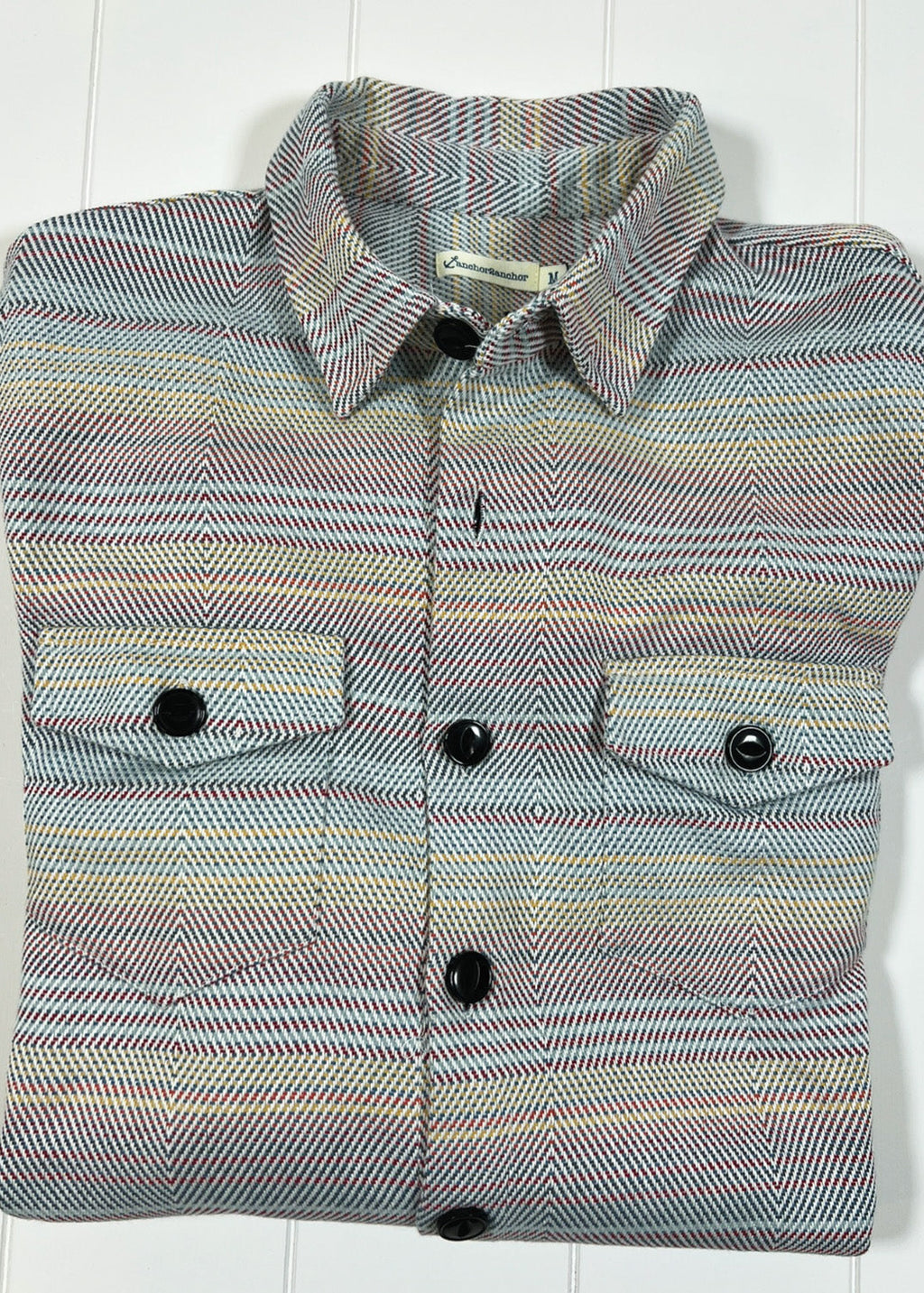Folded multicolored shirt with button details on a white background