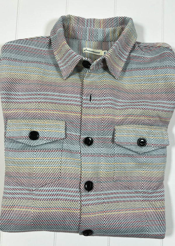 Folded multicolored shirt with button details on a white background