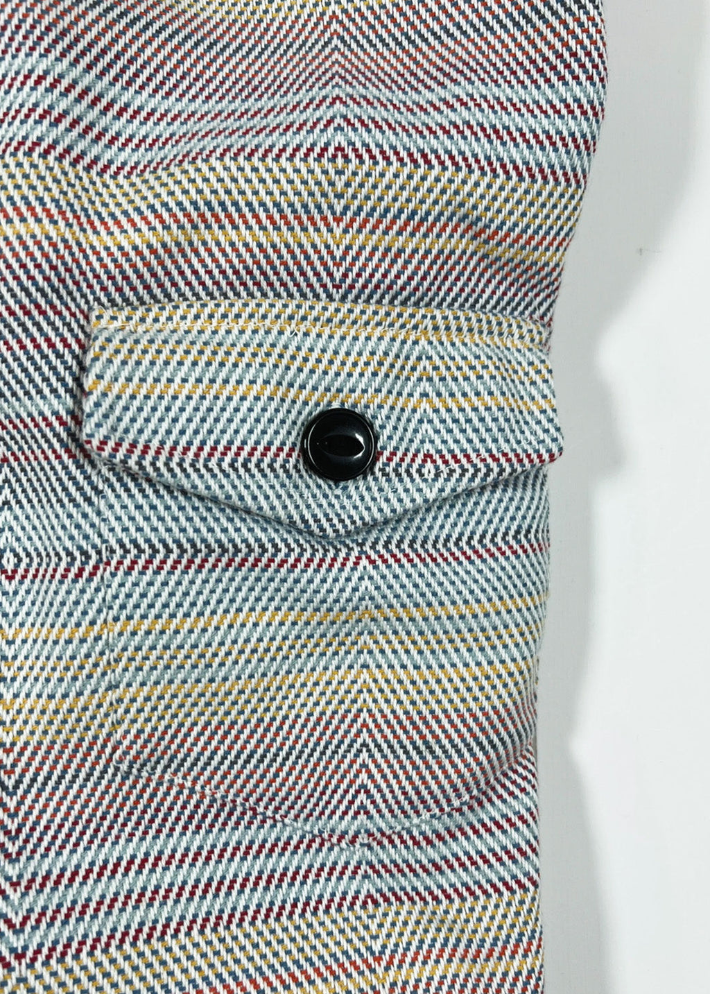 Close-up of a multicolored striped fabric with a button on a white background