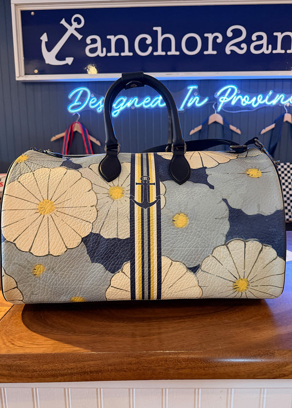 Floral patterned handbag on a wooden surface with a neon sign in the background.