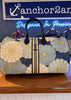Floral patterned handbag on a wooden surface with a neon sign in the background.