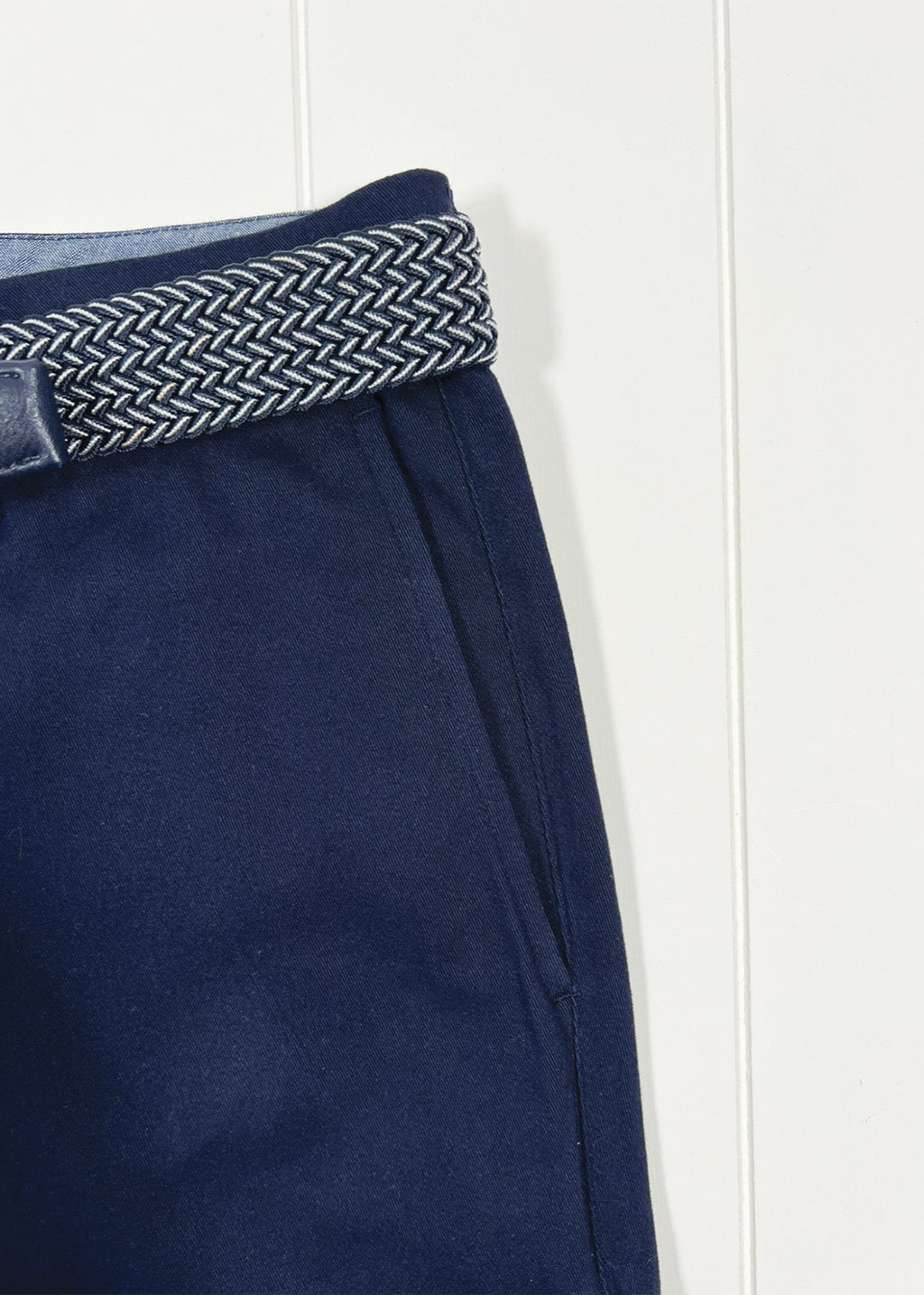 Navy pants with a woven belt on a white background