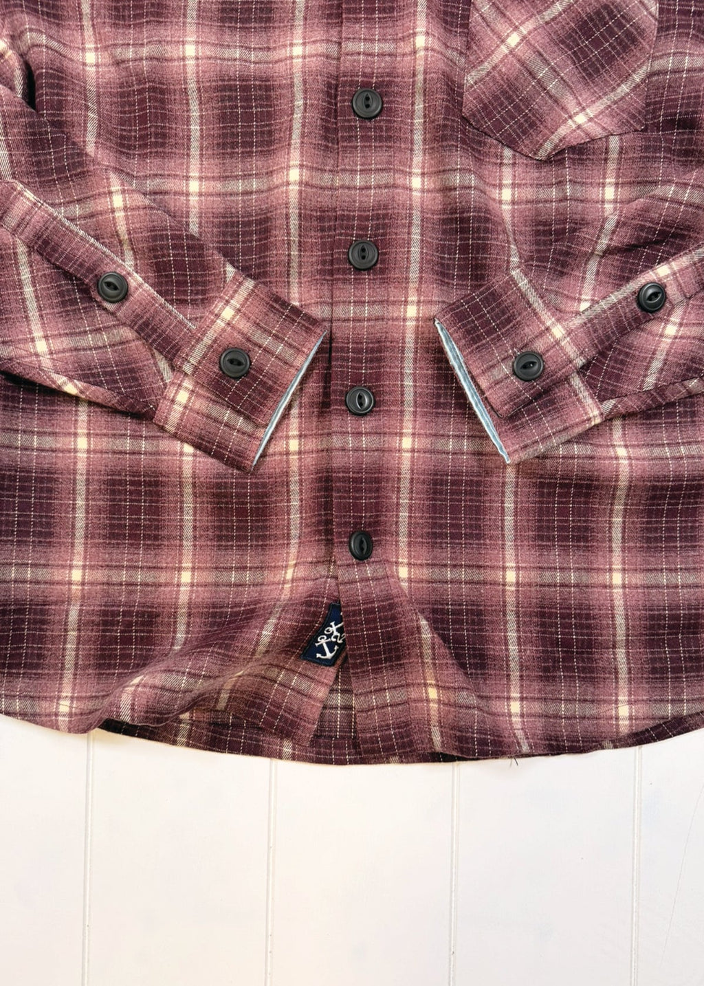 Close-up of a purple plaid shirt with buttons on a white background