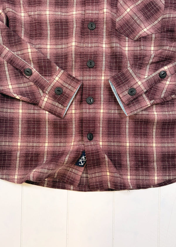 Close-up of a purple plaid shirt with buttons on a white background