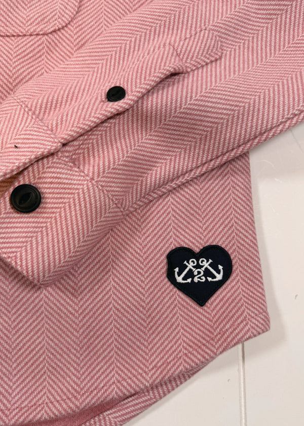 Pink herringbone fabric with a heart-shaped logo featuring an anchor on a white background