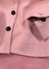 Close-up of a pink herringbone patterned fabric with black buttons.