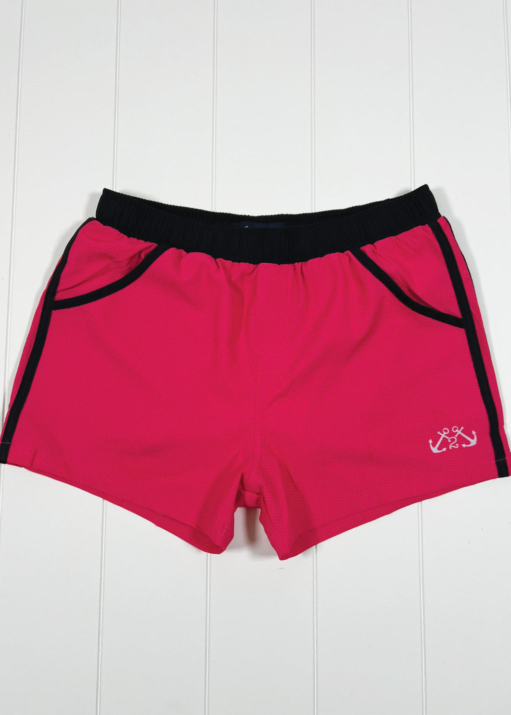 Red shorts with black trim on a white wooden background