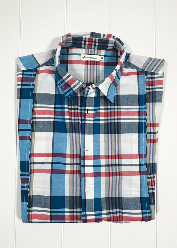 Folded plaid shirt with visible brand label on a white wooden background