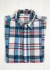 Folded plaid shirt with visible brand label on a white wooden background