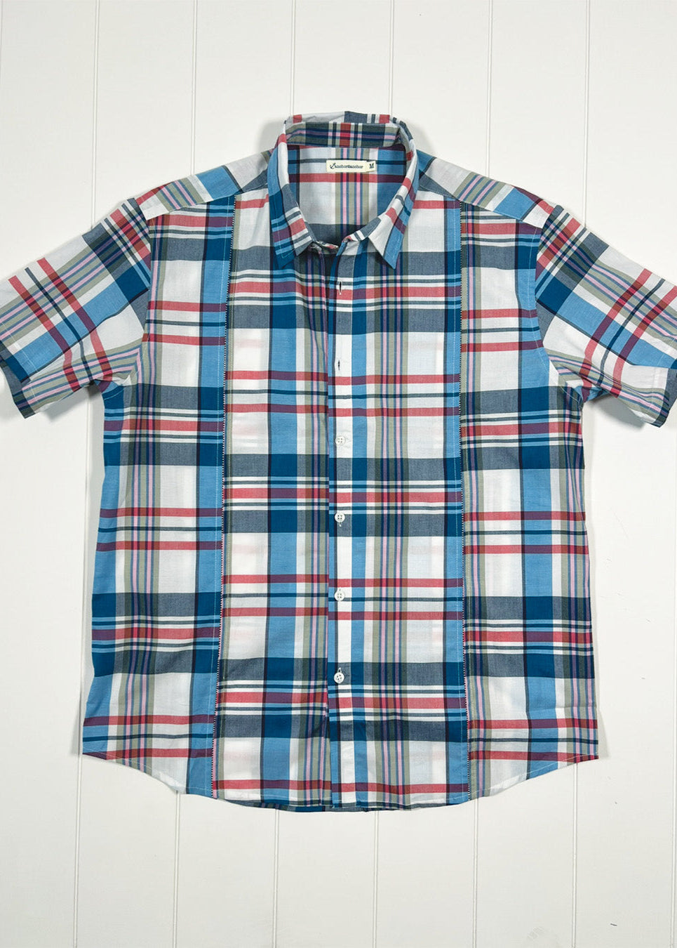 Plaid shirt with short sleeves on a white wooden background