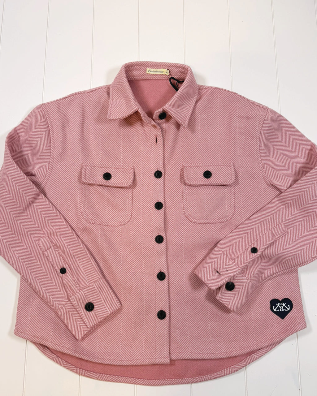 Pink checkered shirt with black buttons on a white background