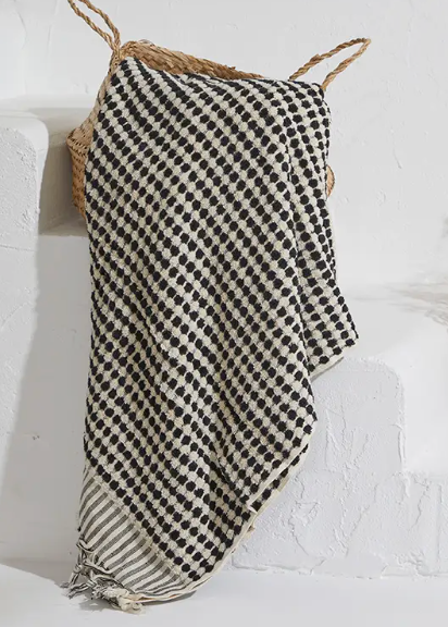 Black and white checkered towel draped over a white chair against a white wall.