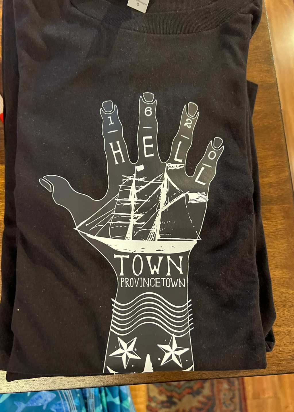 Black t-shirt with white graphic design on a wooden surface