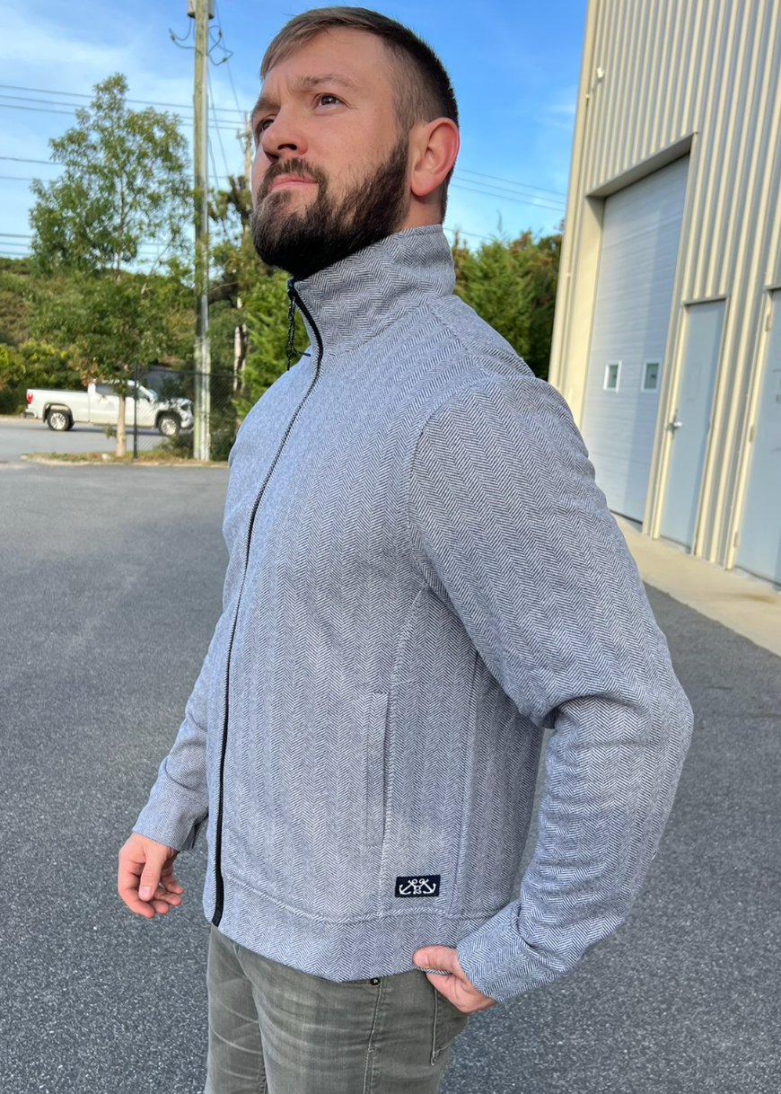 Man wearing a gray jacket standing outdoors near a building