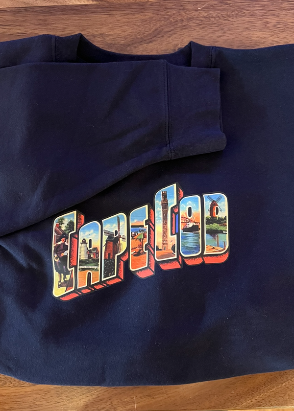 Navy blue sweatshirt with colorful 'CAPE COD' design on a wooden surface