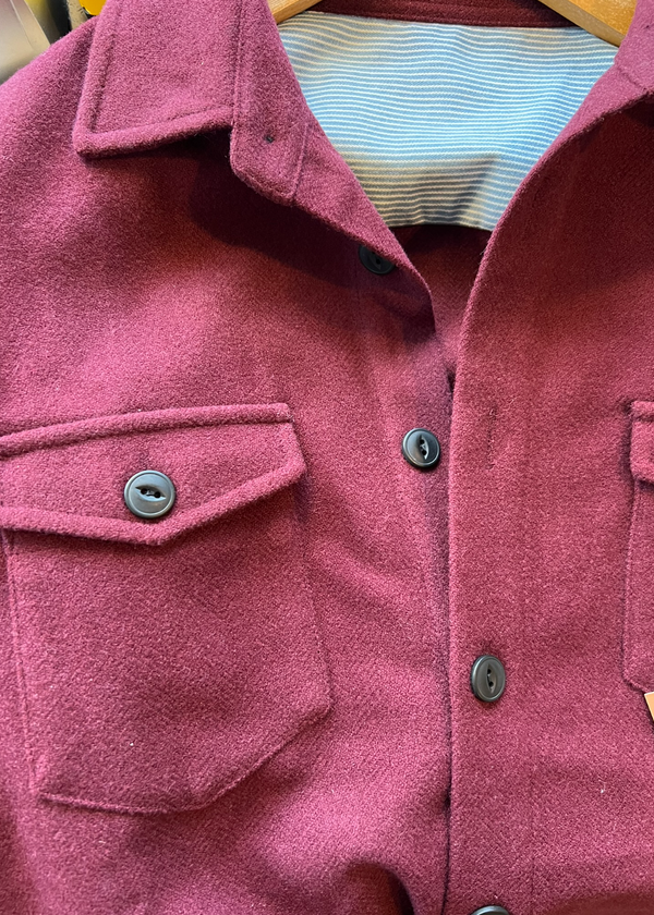 Close-up of a maroon coat with buttons and a collar.