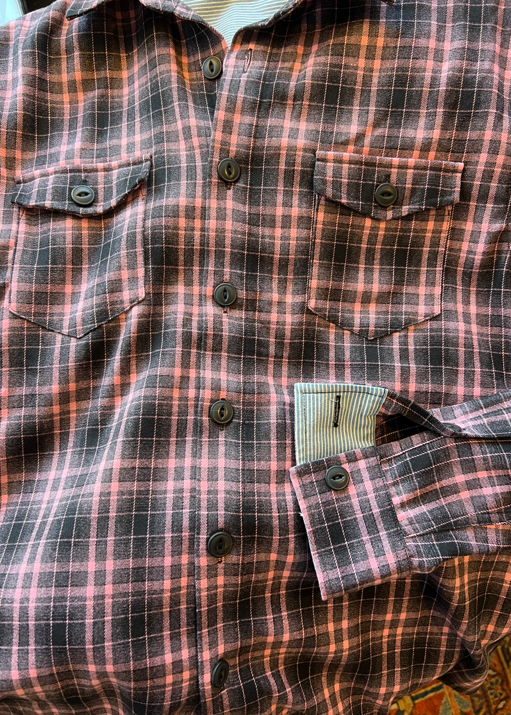 Plaid shirt with buttons and two front pockets on a textured background