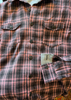 Plaid shirt with buttons and two front pockets on a textured background