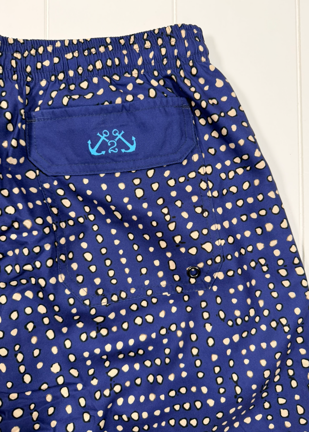 Navy shorts with beige pattern and brand logo on a white background