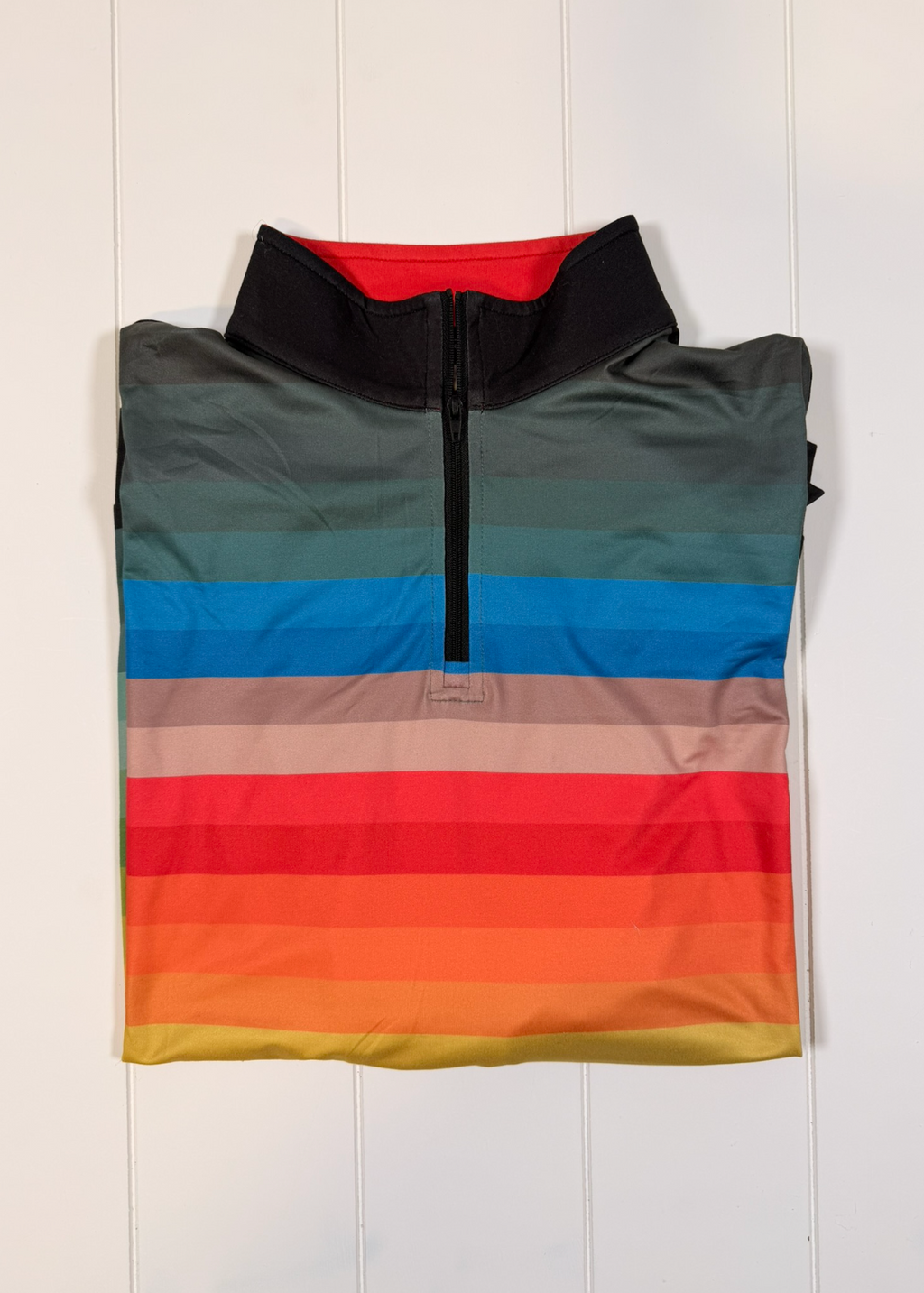 Multicolored striped sleeveless jacket on a white wooden background