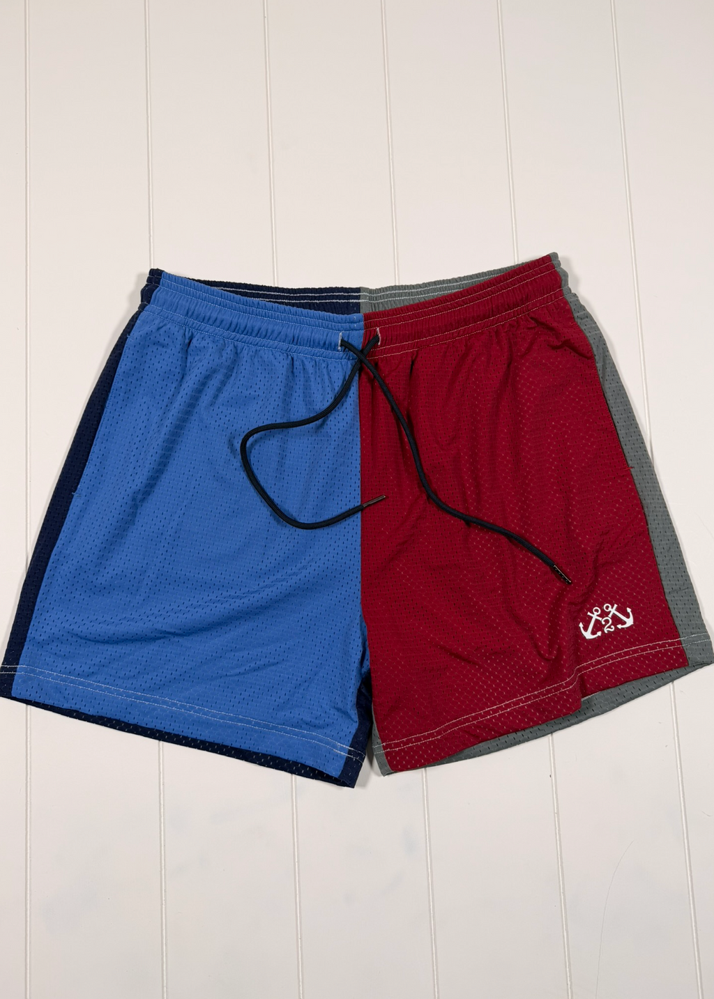 Blue and red shorts with a logo on a white wooden background