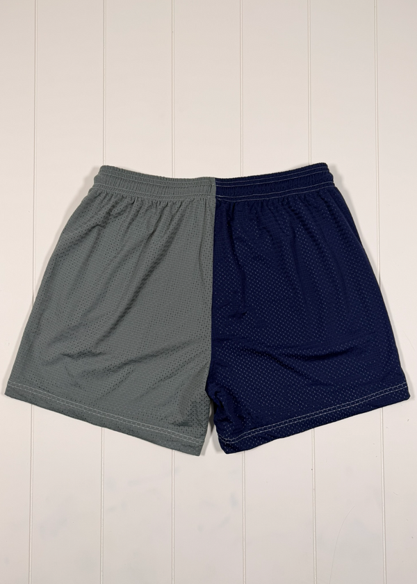 Gray and navy shorts on a white wooden surface