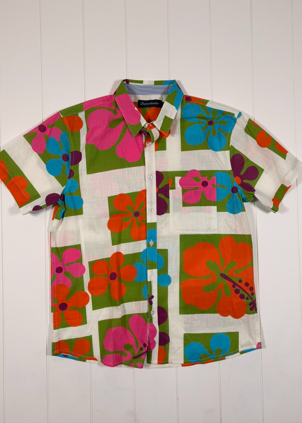 Colorful floral shirt with a brand label on a white wooden background