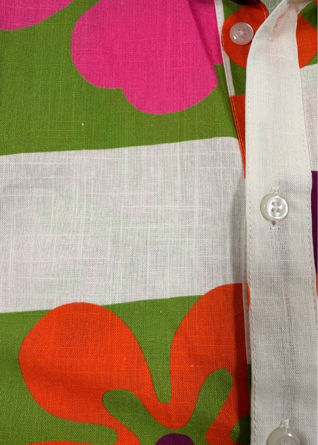Close-up of a fabric with colorful floral patterns and a white shirt collar.