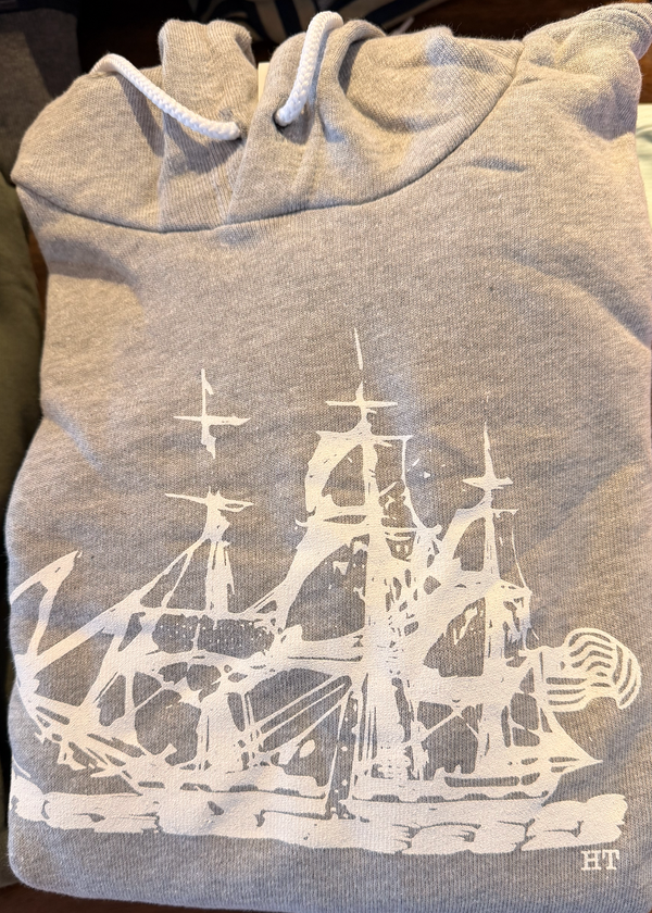 Gray hoodie with a white ship design and 'HT' logo on a wooden surface